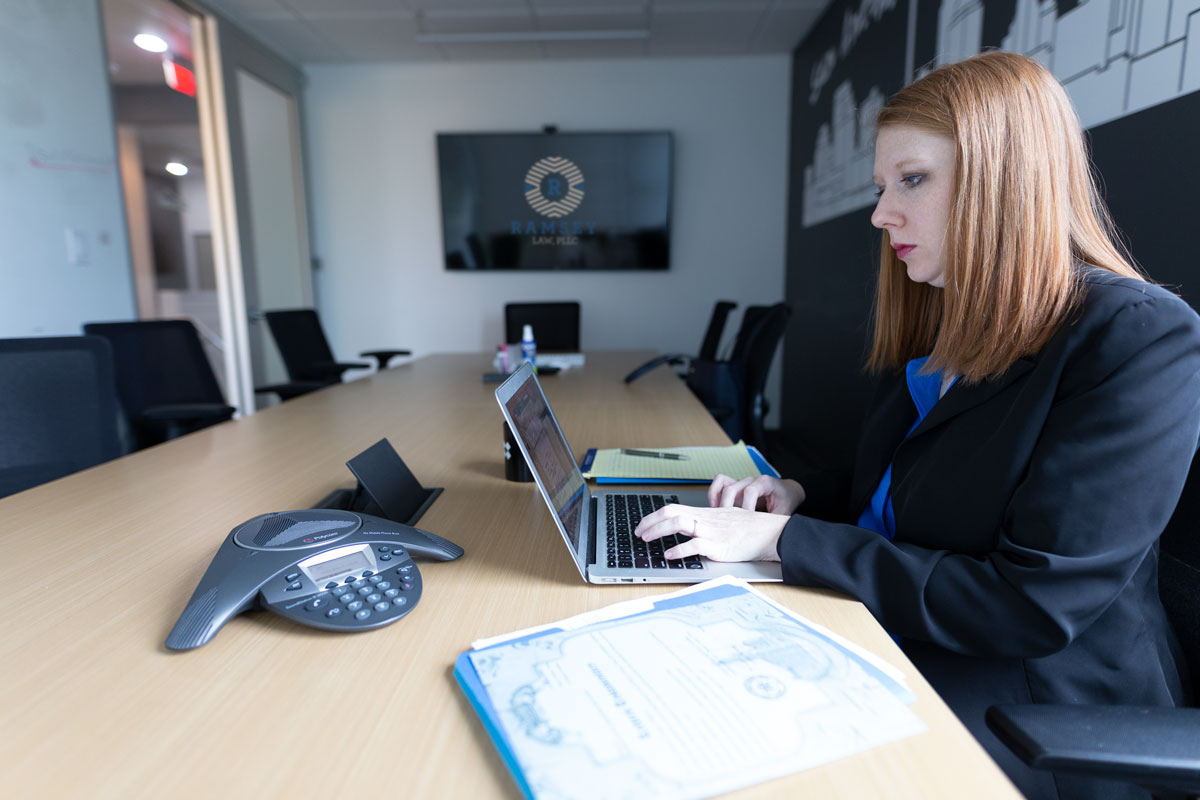 Lawyer Amber Ramsey working on laptop and documents in conference room